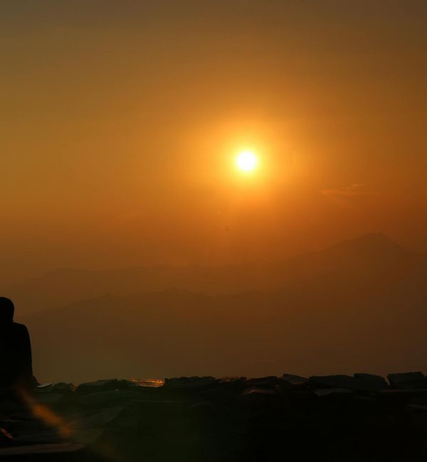 Silhouette of a person in a meditation pose against a warm background.